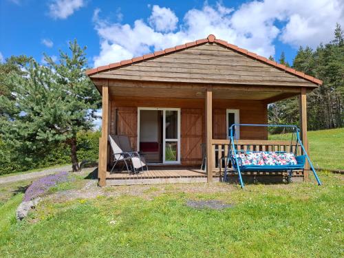 a small cabin with a swing in a field at Chalets au bord du lac de Lavalette in Lapte