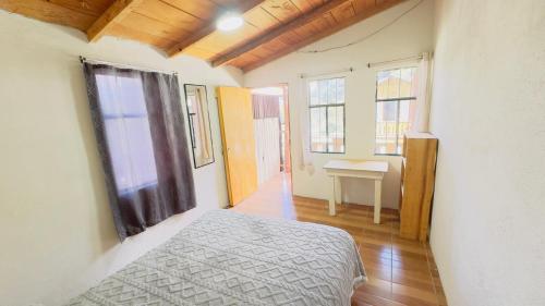 a bedroom with a bed and a table and windows at Luminous Haven Atitlan #1 in San Marcos La Laguna