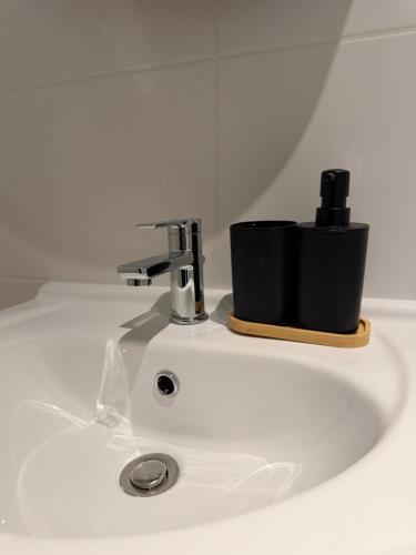 a sink with a faucet and a black cup on it at URBAN House Vienna in Gerasdorf bei Wien