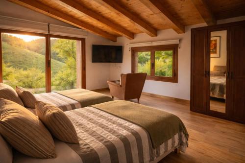 a bedroom with two beds and a large window at RINCON DE MUTILOA Balcón del Aitzgorri HabTuristica in Mutiloa