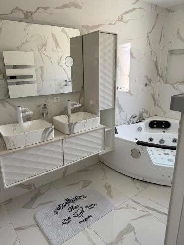 a bathroom with two sinks and a tub and a mirror at Villa avec piscine jacuzzi et sauna in Saint-André-de-Cubzac