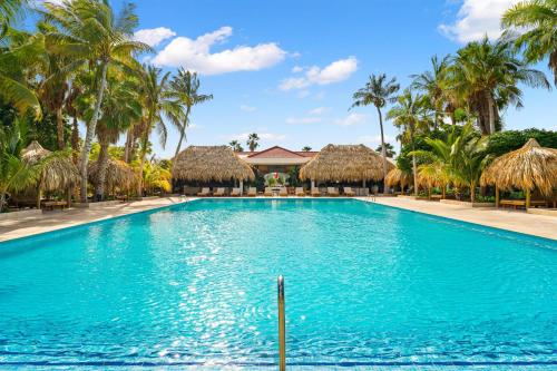 a swimming pool with palm trees and huts at Sonesta Hotels & Resorts Livingstone Curacao in Willemstad