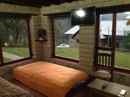 a bedroom with a bed and a tv on a wall at Cabañas Hojarasca in Mineral del Chico