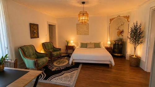 a bedroom with a bed and two chairs at Les jardins d'Elise in Lure