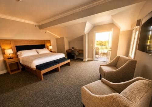 a bedroom with a bed and a couch and a chair at The Cape Club Golf Resort in Falmouth