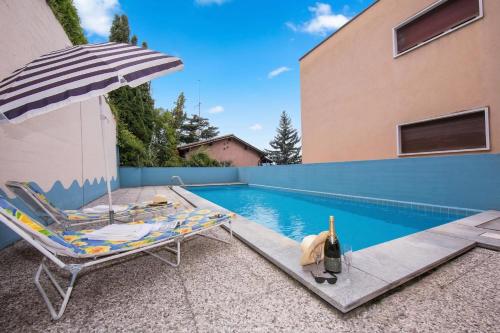 a chair and an umbrella next to a swimming pool at Aldesago Panoramica with shared Pool and Lugano View - Happy Rentals in Aldesago