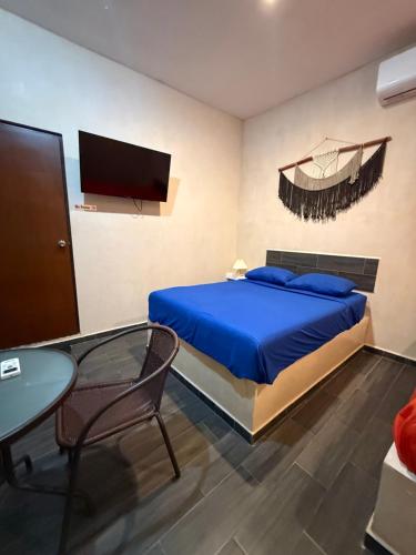 a bedroom with a bed and a table and a tv at Casa Faustos in Mérida