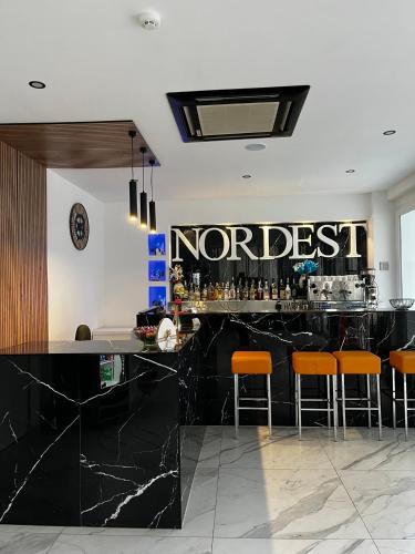 a bar with orange bar stools and a sign that reads northeast at Hotel Nord Est in Riccione