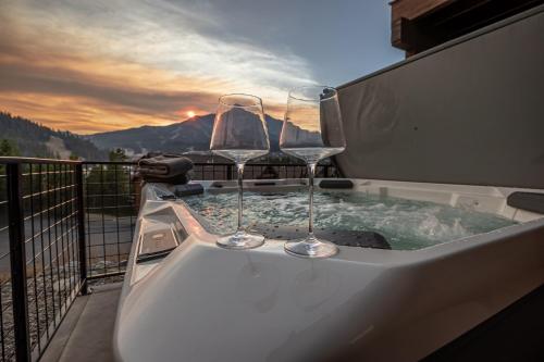 two wine glasses sitting on a hot tub on a balcony at Alpenglow Condo 26A in Big Sky