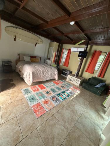 a bedroom with a bed and a rug on the floor at Los Machos surf shack in Ceiba