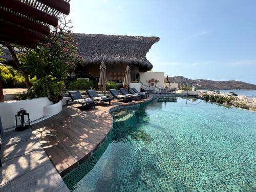 a swimming pool with chairs and a resort at Tentaciones Boutique Hotel - Ocean View & Private Pools - Adults Only in Zihuatanejo