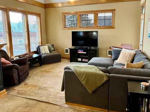 a living room with couches and a flat screen tv at Cape Kiwanda Hideaway in Pacific City