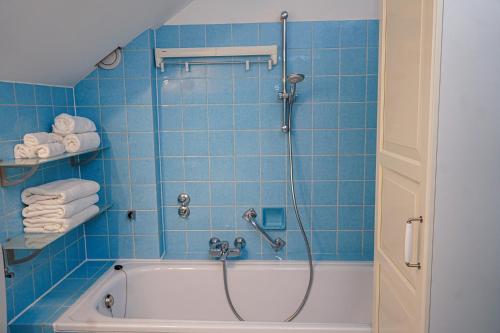 a blue tiled bathroom with a tub and a shower at Appartement Swing in Mittelberg