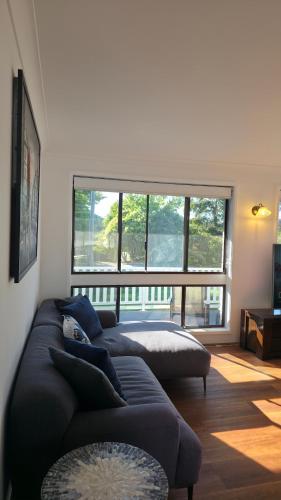 a living room with two couches and a large window at Spacious & Sun-Filled Highlands Retreat in Moss Vale