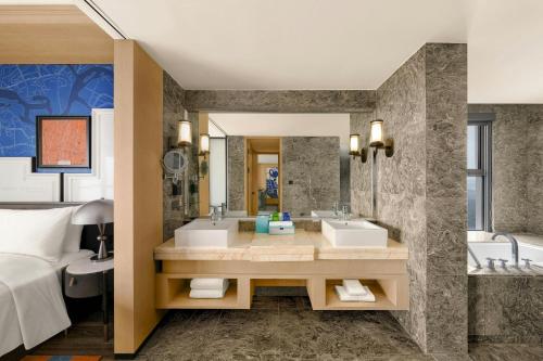 a hotel bathroom with two sinks and a bed at Le Méridien Changzhou in Changzhou