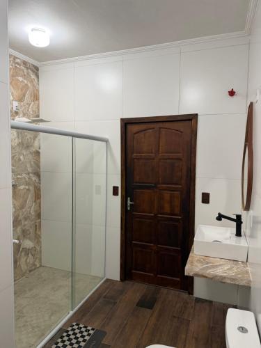 a bathroom with a glass door and a sink at Villavera - Caragua Centro in Caraguatatuba