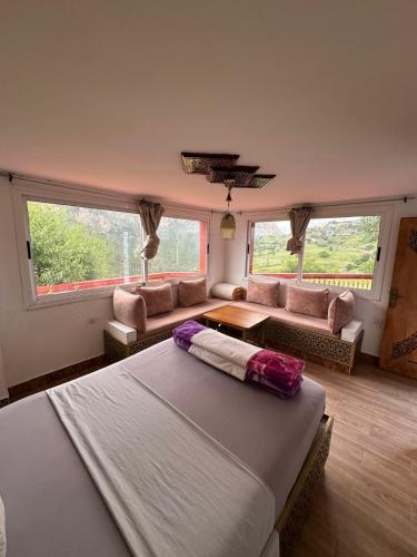 ein Schlafzimmer mit Bett, Sofa und Fenstern in der Unterkunft Complexe rueda in Ouslaf