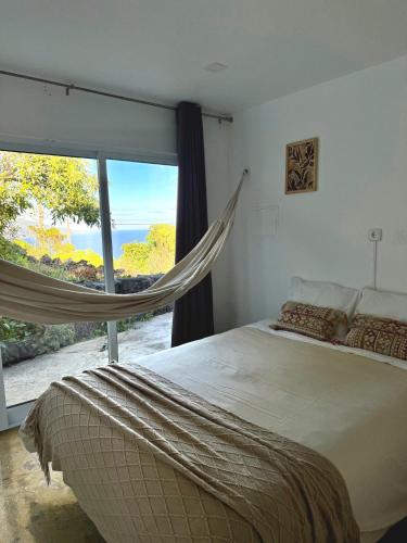 a bedroom with a hammock in front of a window at Bruma do Pico House in Lajes do Pico