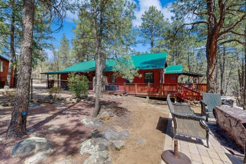 a red cabin with a green roof in the woods at Wild West Wonder in Pinetop-Lakeside