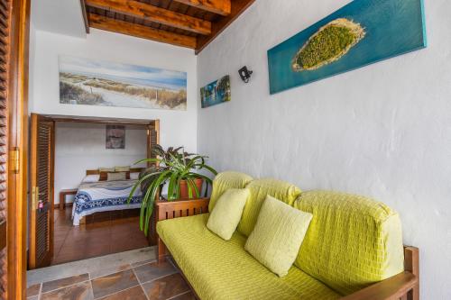 a living room with a yellow couch and a bedroom at Finca Villanueva in Mala