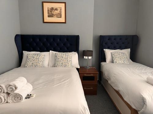 a bedroom with two beds and a blue headboard at Regent Hotel in Eastbourne