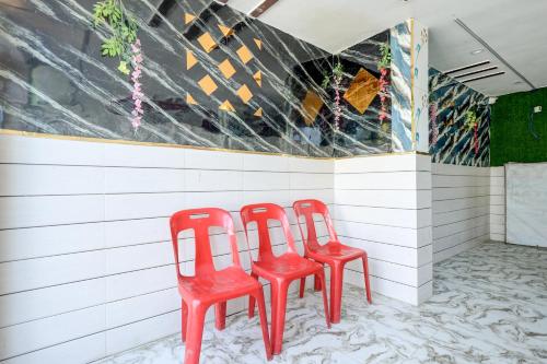 three red chairs sitting next to a wall at Hotel O S.R GRAND HOTEL & RESTAURANT in Kānpur
