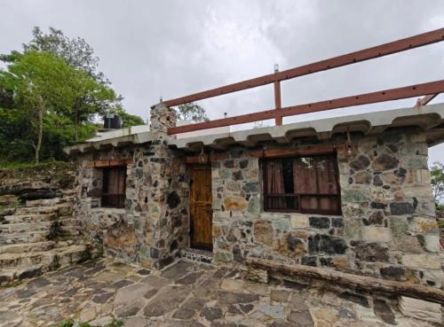 an old stone house with a wooden door at Cabañas el amanecer Jacala in Cuetzalán del Progreso