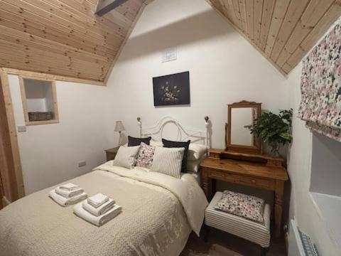 a bedroom with a bed with a mirror and a table at Mag Byrne's Cottage in Sandy Ford
