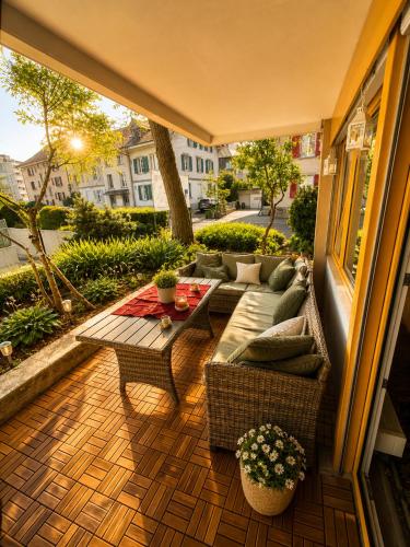 a patio with a couch and a table on a balcony at Bern Garden Residence 152m Luxury Apartment in Bern