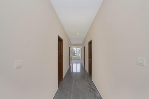 a hallway with white walls and a white ceiling at Hotel O Manu Residency in Bangalore