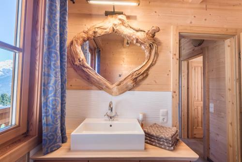 a bathroom with a sink and a heart shaped mirror at Steineralm in Schwersberg