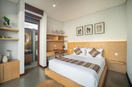 a bedroom with a large white bed and a bathroom at Dahayu Villa Ubud in Ubud