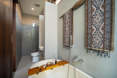 a bathroom with a tub and a toilet and a sink at Dahayu Villa Ubud in Ubud