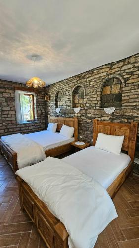 a bedroom with two beds and a brick wall at Anderr stone Boutique in Gjirokastër