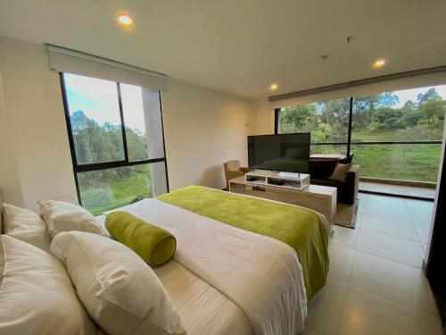 a bedroom with a large bed with a television and a couch at Hotel Rioverde Living Suites in San Antonio de Pereira