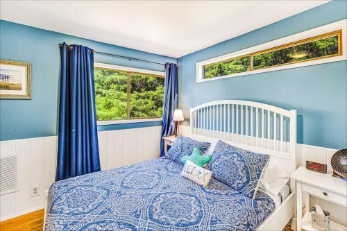 a blue bedroom with a bed and two windows at Cozy Copalis Beach Cottage Escape in Copalis Beach