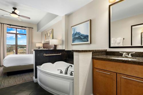 a bathroom with a tub and a sink and a bed at Club Wyndham Great Smokies Lodge in Sevierville