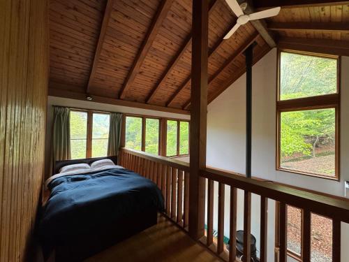 a bedroom with a bed in a room with windows at Cabin A MtFuji view, BBQ, lake Saiko 3mins, hammock, wood deck in Narusawa