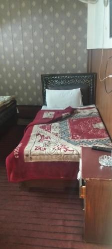 a bedroom with a bed with a red comforter at Hamala Inn Hotel in Abbottabad