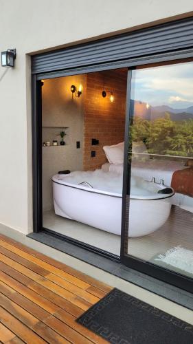 a bedroom with a tub and a bed in a window at Casa Chalé dos Pinhas - Chalé Romântico e Aconchegante - Hidromassagem - Lareira - Vista da Montanha - Próximo a Campos do Jordão in Santo Antônio do Pinhal