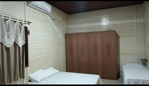 a bedroom with two beds and a wooden cabinet at Chacara castanheira in Ariquemes