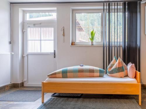 a bed with pillows on it in a room with a window at Klein Hintermühltalhof in Itter