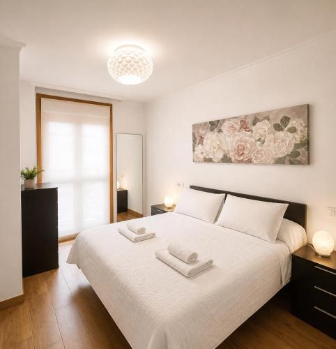 a bedroom with a white bed with two towels on it at RELAX VIVEIRO in Viveiro
