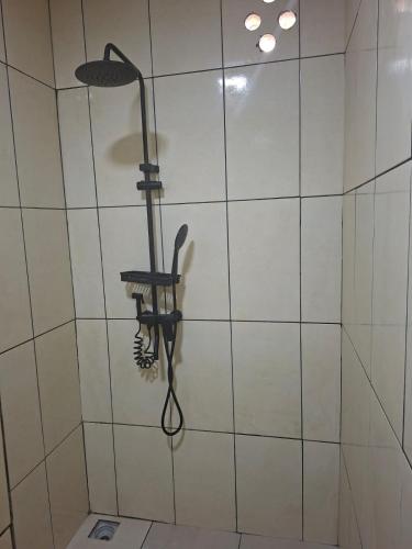 a shower with a shower head hanging on a wall at Zara Appartement in Paramaribo