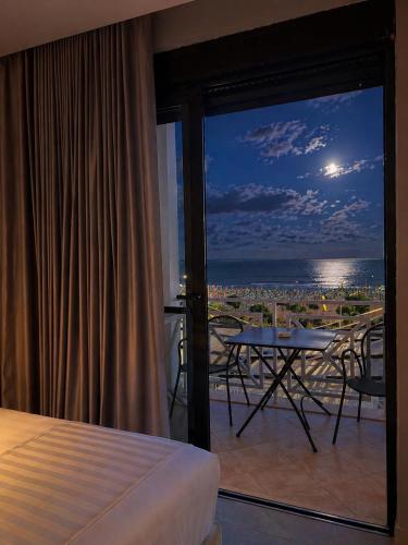 a bedroom with a balcony with a view of the ocean at Hotel President in Shëngjin