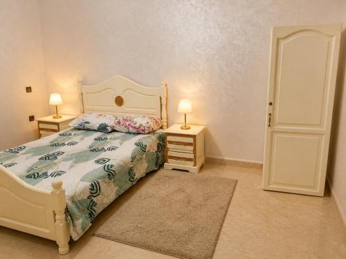 a bedroom with a bed and two lamps and a door at Appartement Riad à Taroudant Piscine Privée & Grand Jardin, Séjour Unique in Taroudant