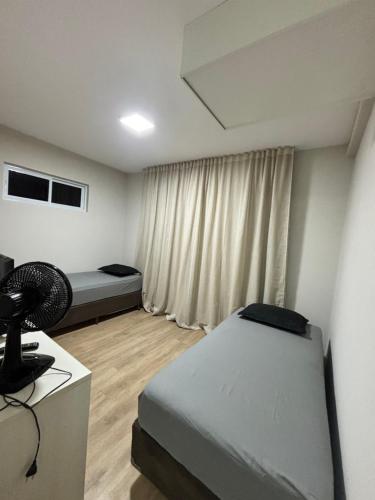 a bedroom with two beds and a desk with a fan at Kitnet bem equipada para 2 pessoas in Curitiba