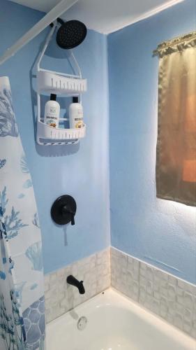 a bathroom with a bath tub with a blue wall at Comfort Suites - Studio Two in La Fargue
