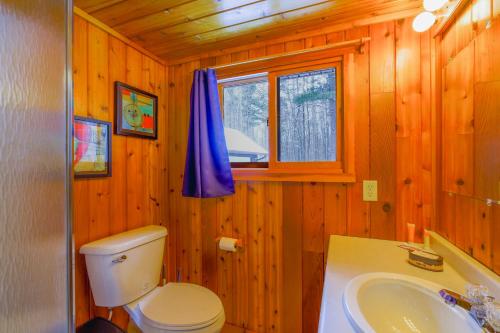 a bathroom with a toilet and a sink and a window at Riverside Motel in Hayward