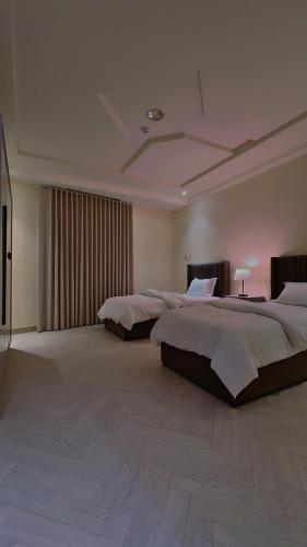 a large bedroom with two beds and a television at شقة سُبات الفندقية الفاخرة in Buraydah